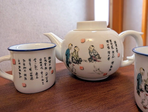 Porcelain tea cup and tea pot with three people playing Go and some Chinese Caligraphy